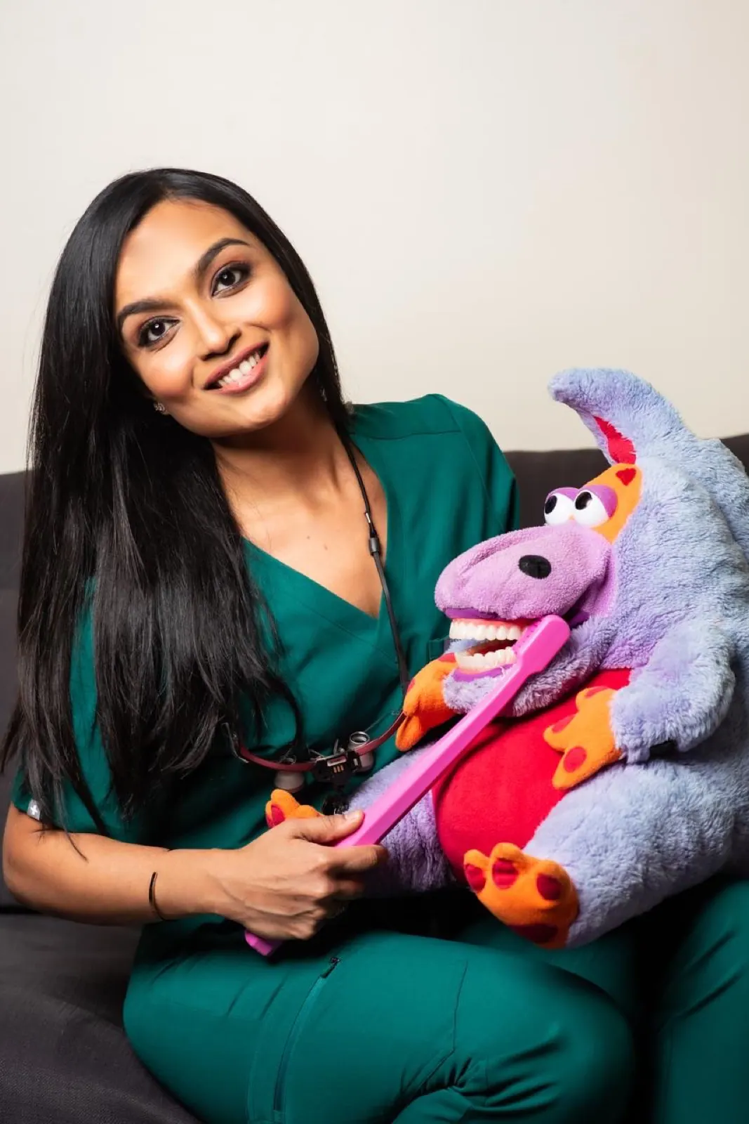 Dr. Nidhi with her dinosaur puppet and a giant toothbrush