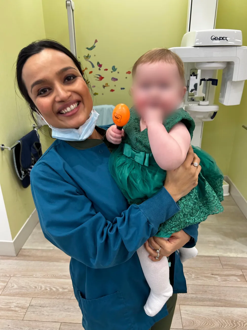 Dr. Nidhi holding a baby after a visit, rattle in hand