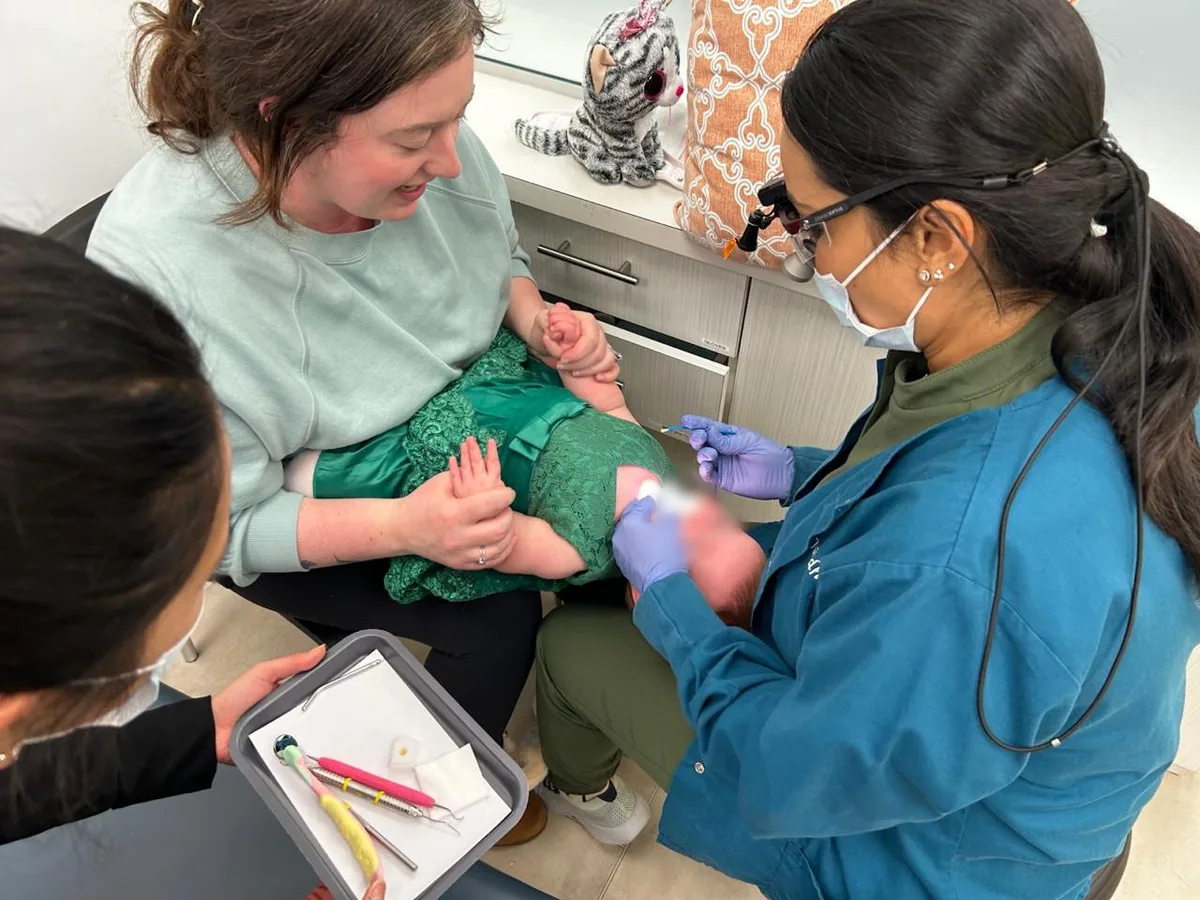 Dr. Nidhi gently examining a baby in a parent's lap