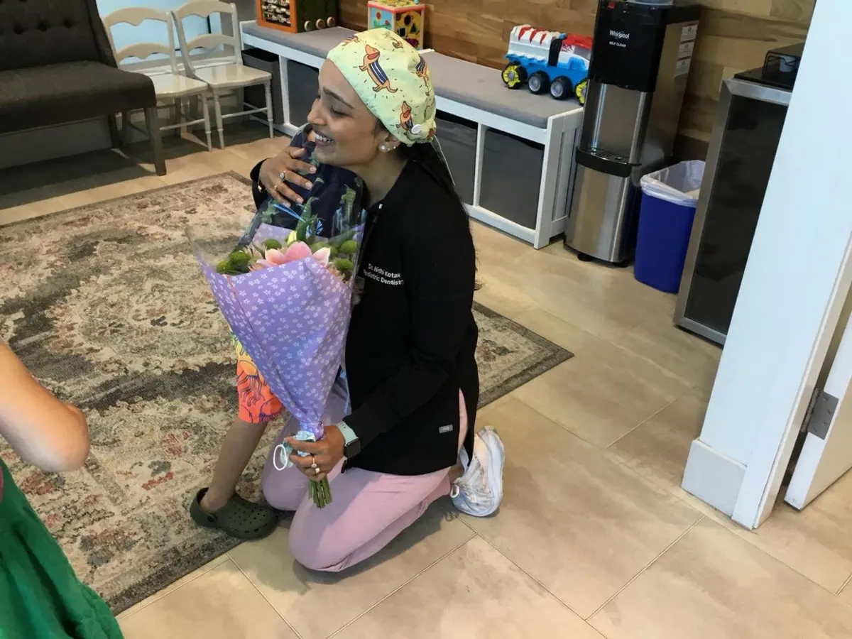 A young patient hugging Dr. Nidhi and handing her flowers