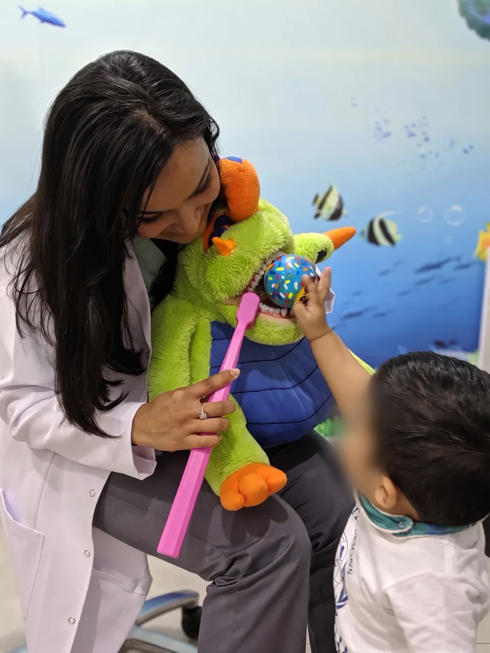 A little boy brushing the teeth of Dr. Nidhi's puppet