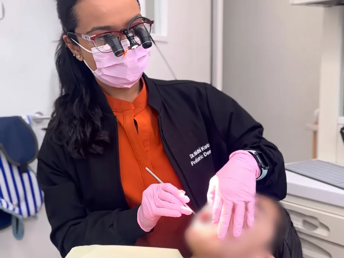 Dr. Nidhi working gently on a child who is resting quietly in the chair